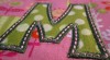 Close-up example of stitched uppercase applique "M"