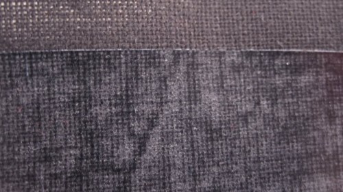 This picture shows black fabric with Fuse-Adhere applied. The top portion is the black fabric only and the bottom portion is the fuse-adhere.